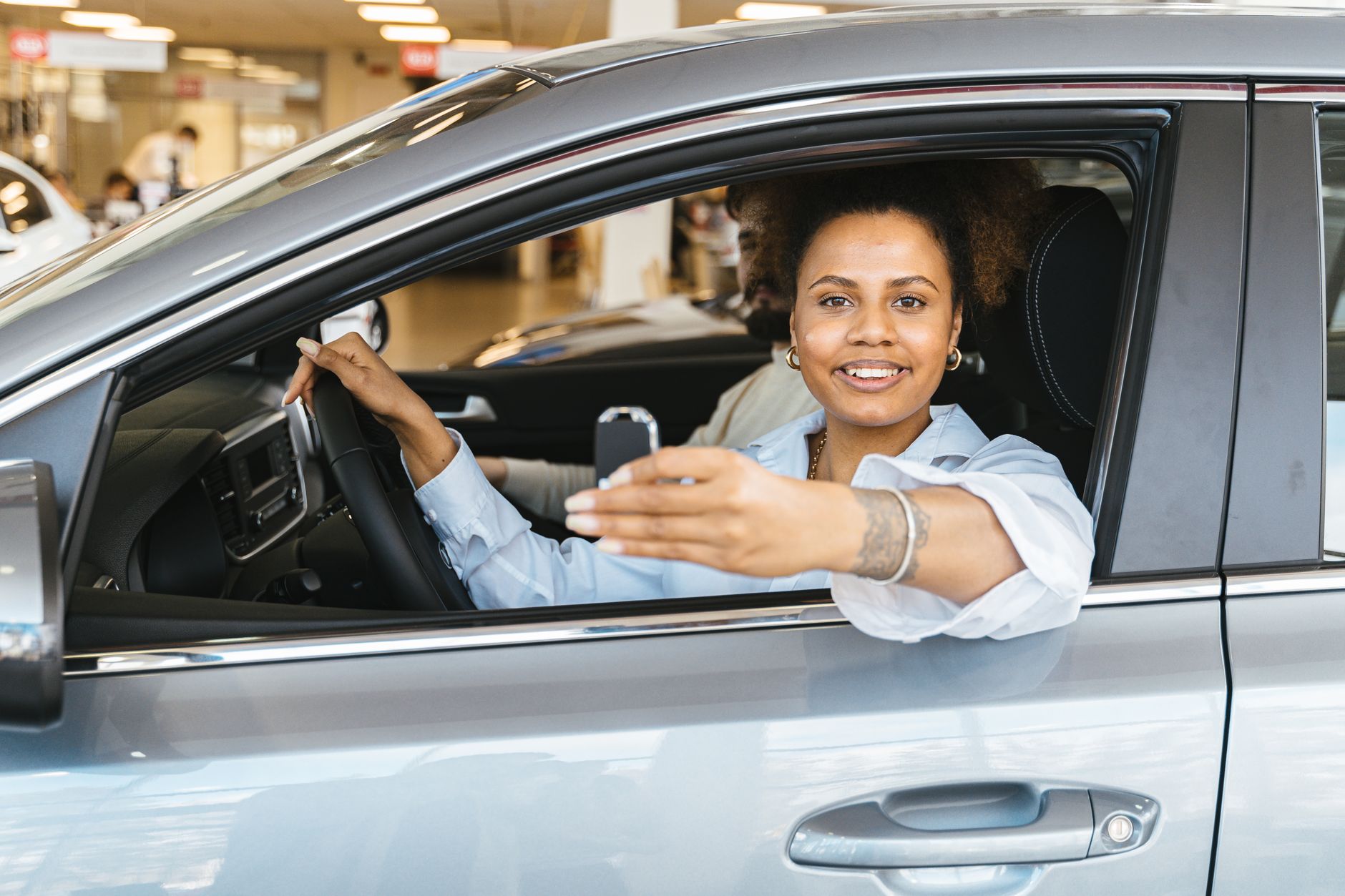 Mulher sorridente dirigindo com as duas mãos no volante